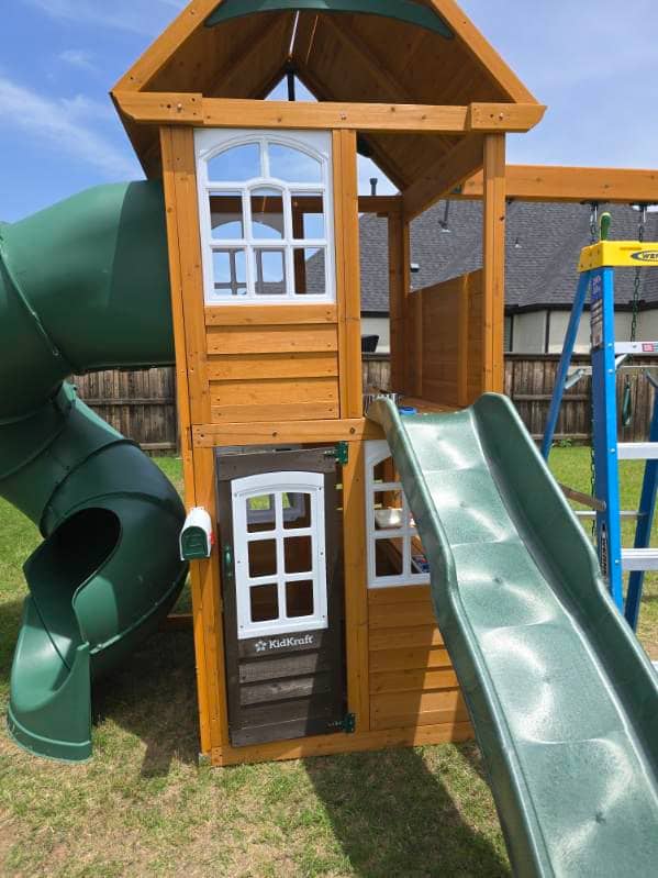 Wooden playset with clubhouse, slide, and swing beam assembled in a yard