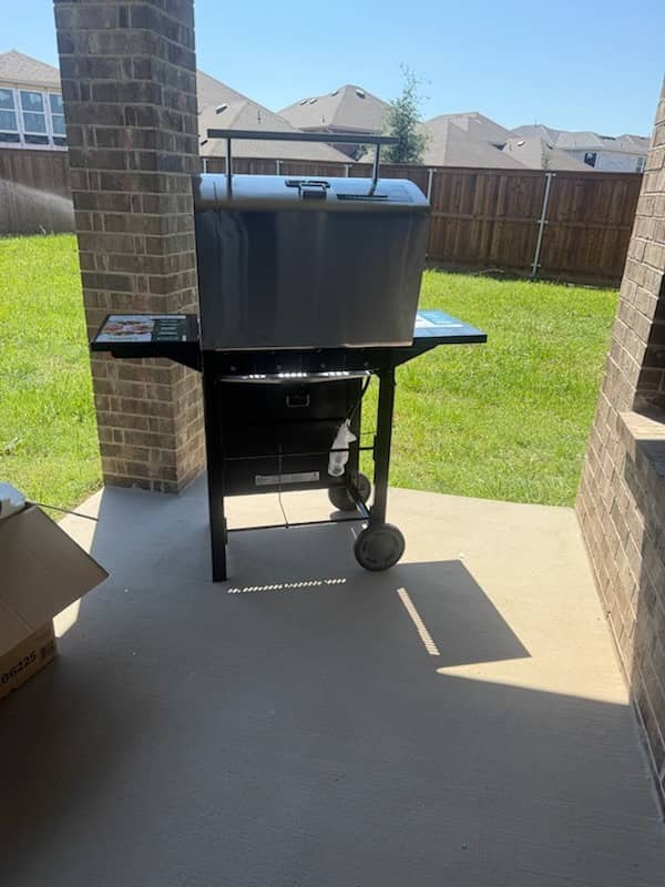 Stainless steel BBQ grill assembled on a covered patio in a Texas backyard