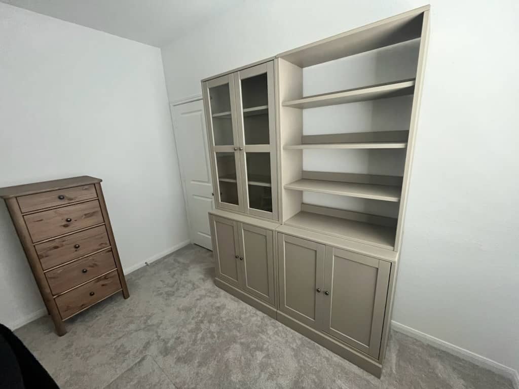 Tall bookshelf unit with glass door cabinet and open shelves assembled in a room