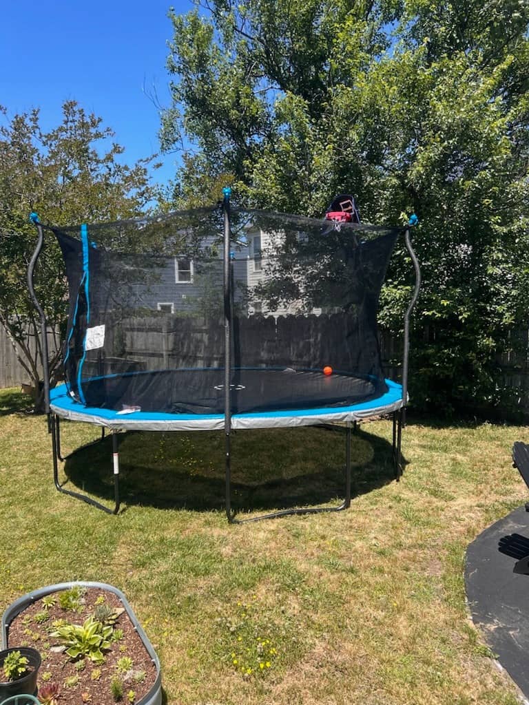 Full-size trampoline with safety net enclosure assembled in a backyard